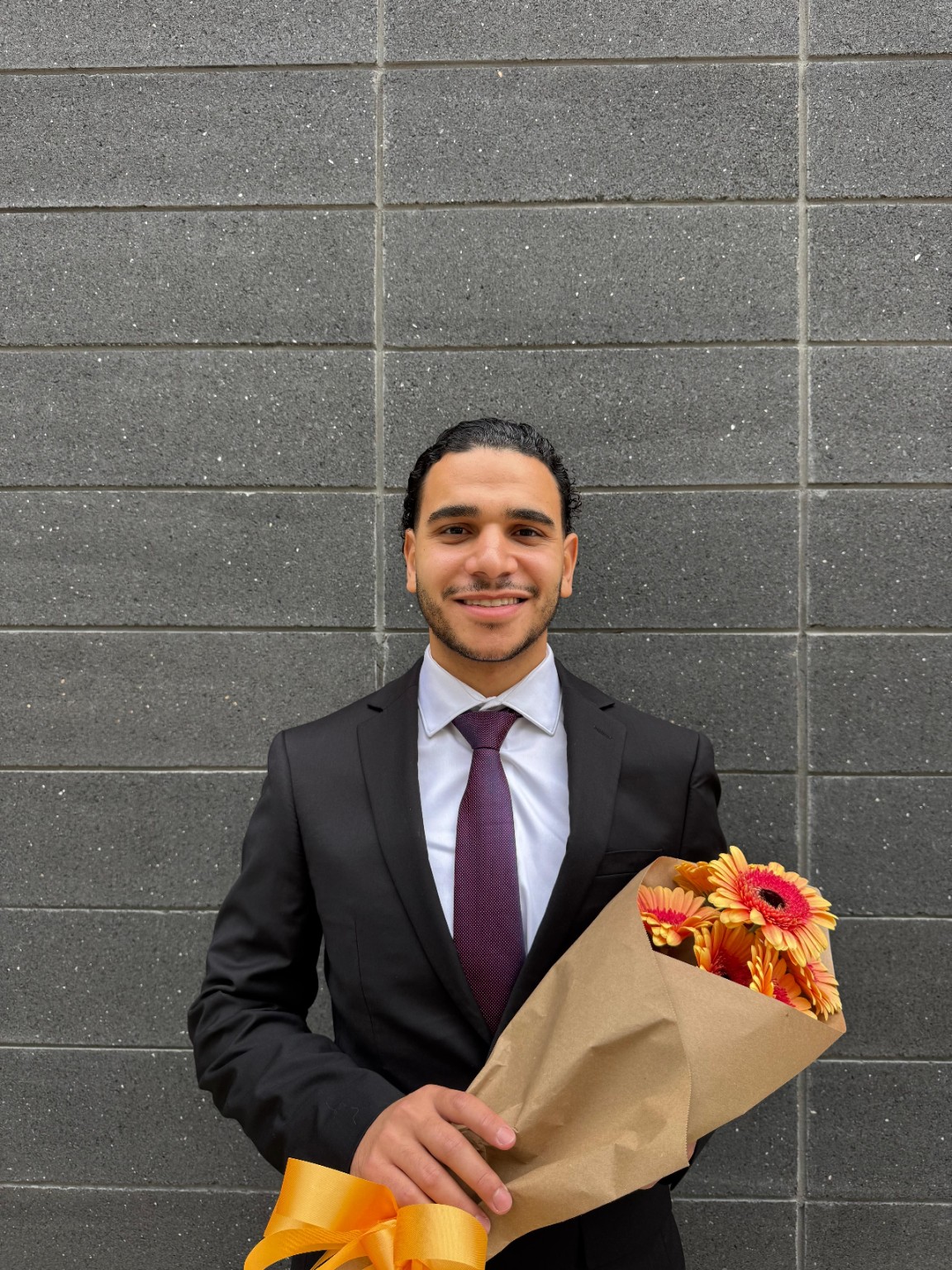 Salman Ayman Youssef smiling in a suit and holding a bouquet